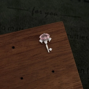 Macro shot of silver key earring featuring oval pink stone and micro-pave white zircons