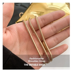 Detail of a flexible gold snake chain strap for an acrylic bag with metallic shine