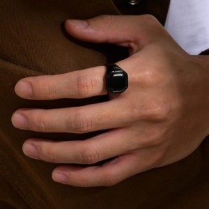 Close-up of a men's black signet ring with a polished square enamel inlay on finger