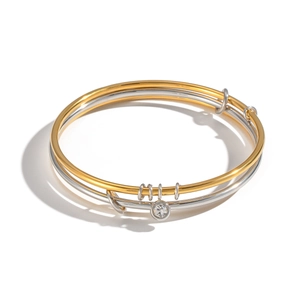 Detail of two-tone gold and silver minimalist bangle with a sparkling zircon charm