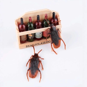 Miniature wooden wine crate with five colorful bottles and two realistic fake cockroaches