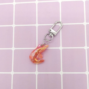 Macro shot of creative mini iridescent shrimp pendant on a silver metal keychain