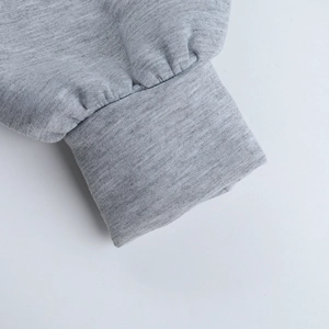 Gros plan détaillé du poignet côtelé gris montrant la texture en coton mélangé