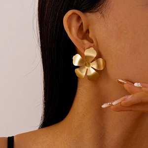 Close-up of golden matte flower earring on female model showing metallic petal detail