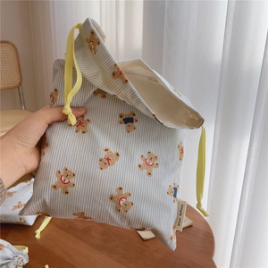 Detailed shot of cotton drawstring bag with blue stripes and bear print held by hand