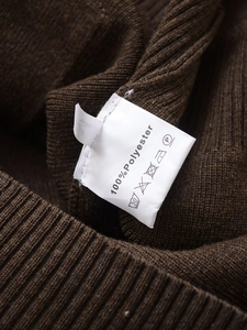 Detail of fabric label showing 100% polyester material and M size on brown knit cardigan