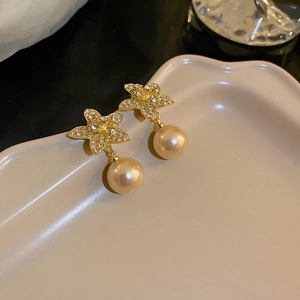 Macro shot of gold starfish earrings with sparkling zircon and champagne pearl detail
