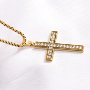 Macro shot of gold-plated cross necklace with rhinestones on a white silk background