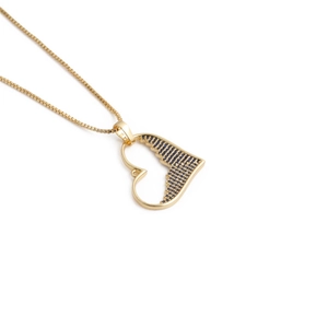 Close-up of golden box chain with heart pendant featuring black textured details and stones
