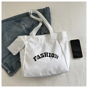 Flat lay of a white large capacity Oxford tote bag with Fashion text and matching mini pouch