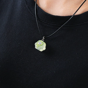 Detail shot of a yellow translucent cat paw resin pendant necklace worn by a model