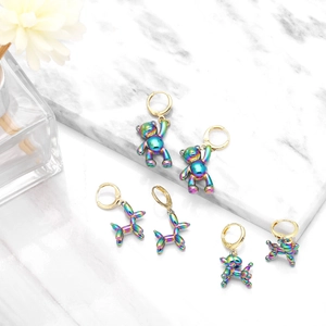 Detailed shot of iridescent balloon dog and bear earrings on white marble surface