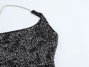 Detail of black dress with sparkling silver sequins and delicate metal chain straps