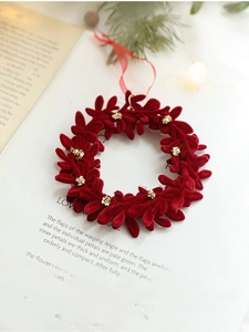 Detail of red flocked Christmas wreath pendant with gold glitter on vintage book page
