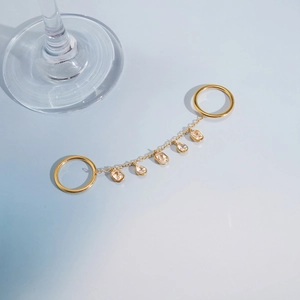 Détail d'une bague double dorée avec chaîne fine et cinq zircons brillants suspendus