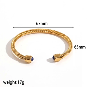 Goldener gedrehter Stahlarmreif mit blauen Edelstein-Enden im offenen Manschettendesign