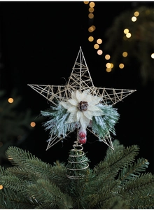 Close-up of golden iron star tree topper with pine cones and red berries detail