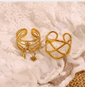Detailed view of layered 18K gold star rings with zircons on white lace background