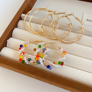Detail view of vintage-style gold-tone hoop earrings with colorful crystals on beige velvet