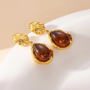 Macro view of vintage gold teardrop earrings with deep amber resin inlay and hammered texture