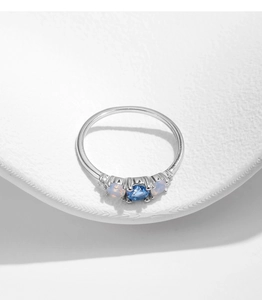 Detail of s925 silver ring with blue crystal and pink opals on white matte surface
