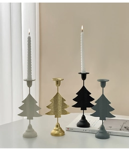 Close-up of four Christmas tree metal candle holders in gold, black, white, and grey