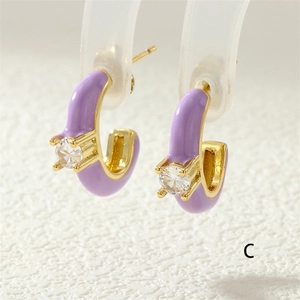 Macro detail of purple enamel C-shaped earring with gold base and zircon inlay