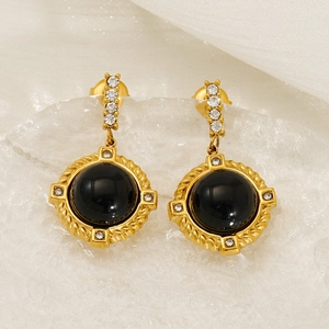 Détail de boucles d'oreilles baroques en obsidienne et or avec cristaux sur soie blanche