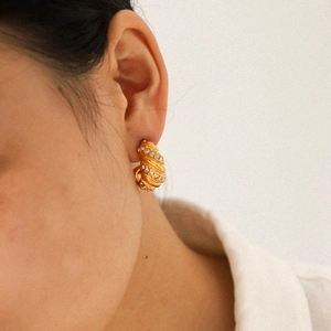 Close-up of 18K gold-plated twisted hoop earring with diamonds on a model's ear