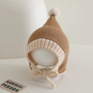 Detail of baby knit elf hat with pom-pom and chin straps showing ribbed texture