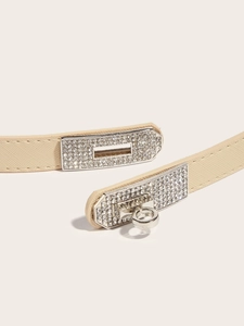Close-up of cream leather belt featuring a silver Kelly lock buckle with sparkling rhinestones