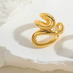 Detailed view of a gold geometric ear cuff with abstract streamlined design on white stone