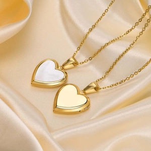 Detailed macro view of gold heart locket necklaces with shell inlay on champagne silk
