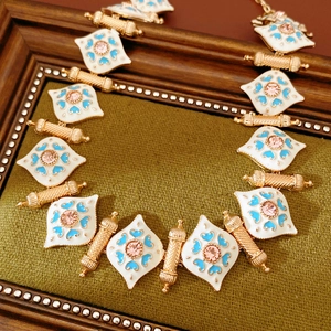 Detail of vintage enamel diamond pendant with blue heart and pink gemstone on green fabric