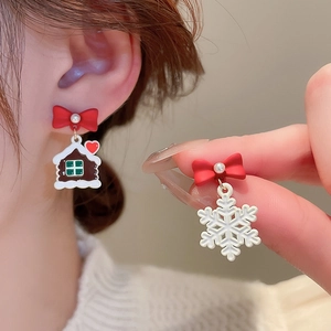 Detailed view of asymmetric Christmas earrings with red bows, gingerbread house and snowflake