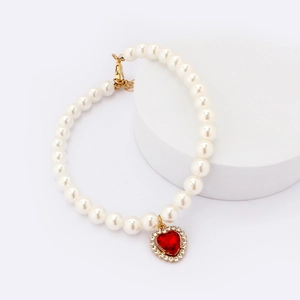Detail of white pearl dog necklace with a sparkling red heart gemstone pendant
