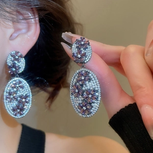 Macro shot of elegant purple zircon flower oval drop earrings with vintage silver setting