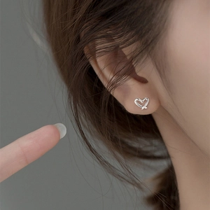 Minimalist S999 sterling silver hollow heart stud earrings worn by model for size view