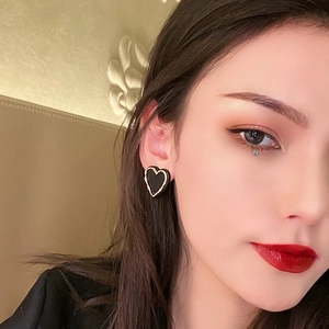 Chic black heart earrings with gold trim worn by a model in a minimalist style