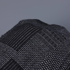 Macro detail of irregular plaid denim flat cap showing high-quality woven texture