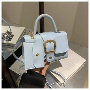 Detail of light blue crossbody bag with gold buckle and matching mini card holder charm