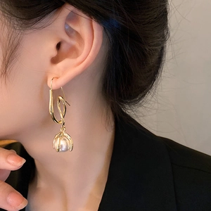 Detail shot of a minimalist gold twisted ear hook earring with a hanging pearl on a model