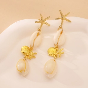 Detalle macro de pendientes colgantes de caracol marino y estrella de mar dorada en plato
