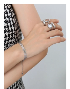 Dettaglio del bracciale geometrico argento e degli anelli sovrapposti sul polso donna