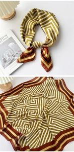 Detailed close-up of a geometric silk scarf showing the elegant knot and mustard yellow pattern