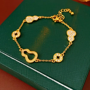 Detailed macro view of 24k gold-plated bracelet with gourd and coin charms on a dark box