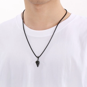 Detail view of a black stainless steel half-heart pendant necklace worn by a person