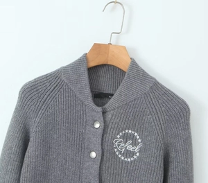 Close-up of Refeel letter embroidery and star detail on grey knitted cardigan sweater