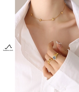 Gros plan d'un collier à cœurs et d'une bague smiley en acier inoxydable doré pour femme