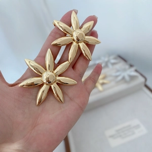 Elegant gold sunflower earrings for women made of polished mirror metal on a palm